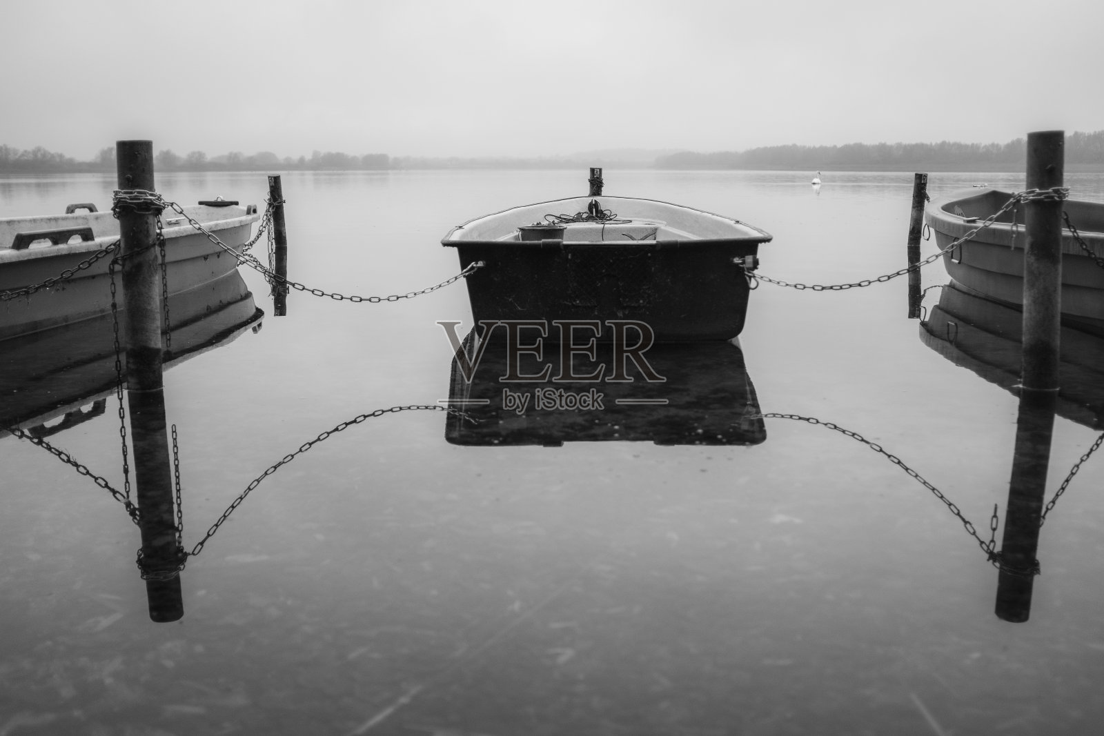 湖面上有几艘划艇，它们被拴在一起，水面平静如镜照片摄影图片