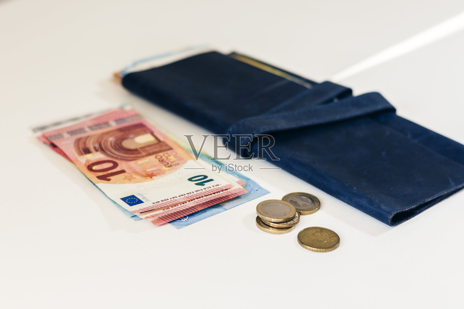 近距离看钱的欧元钞票在蓝色的钱包和硬币在白色的背景照片摄影图片