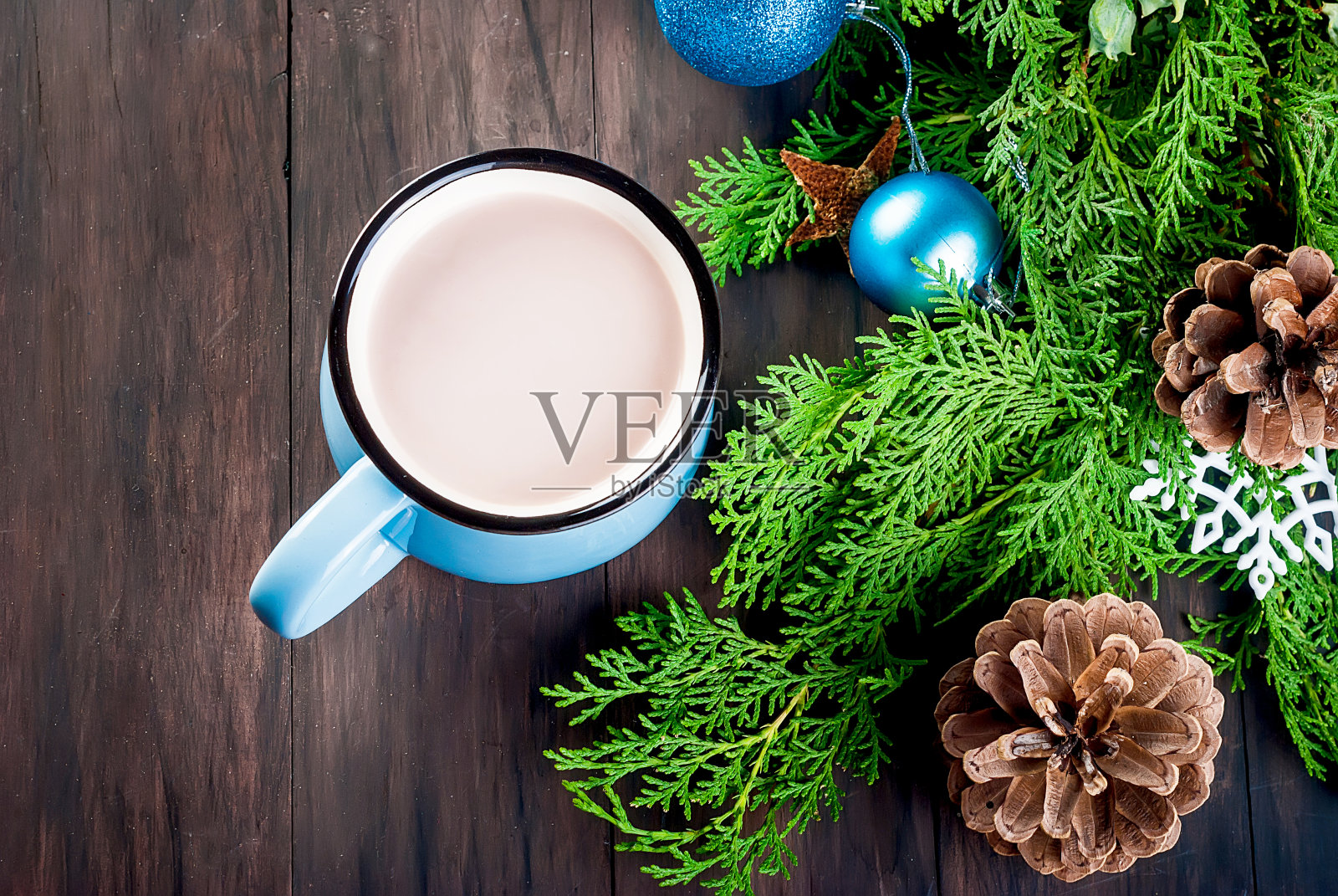 蓝色杯子里的热可可放在黑色的木桌上，还有圣诞装饰，礼物，松果，包装纸。制作圣诞礼物俯视图，拷贝空间。寒假的概念。照片摄影图片