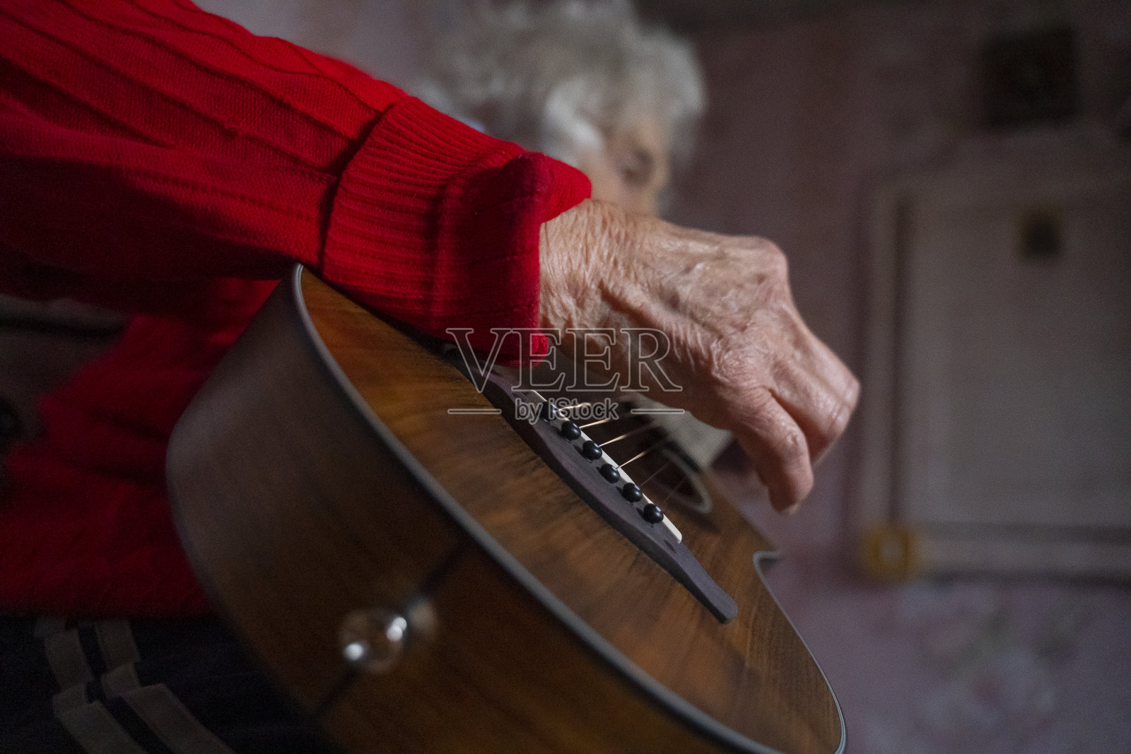 一个老人在弹吉他。音乐和娱乐。一个有皱纹的祖母的肖像，享受音乐和玩得开心。照片摄影图片