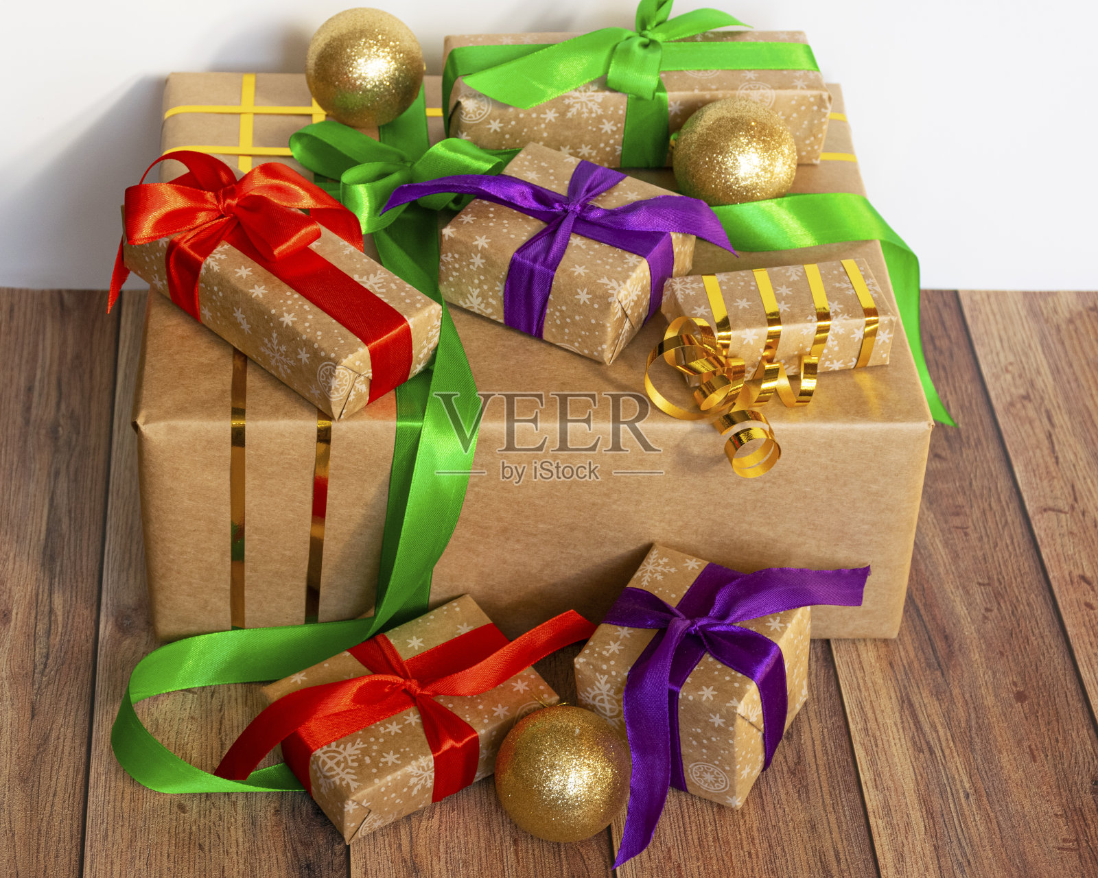 礼物用牛皮纸包装，用缎带绑上新年玩具，放在木制的背景上。照片摄影图片