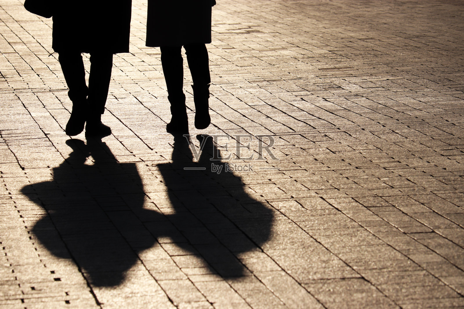 两个女人走在街上，人行道上有剪影和影子照片摄影图片