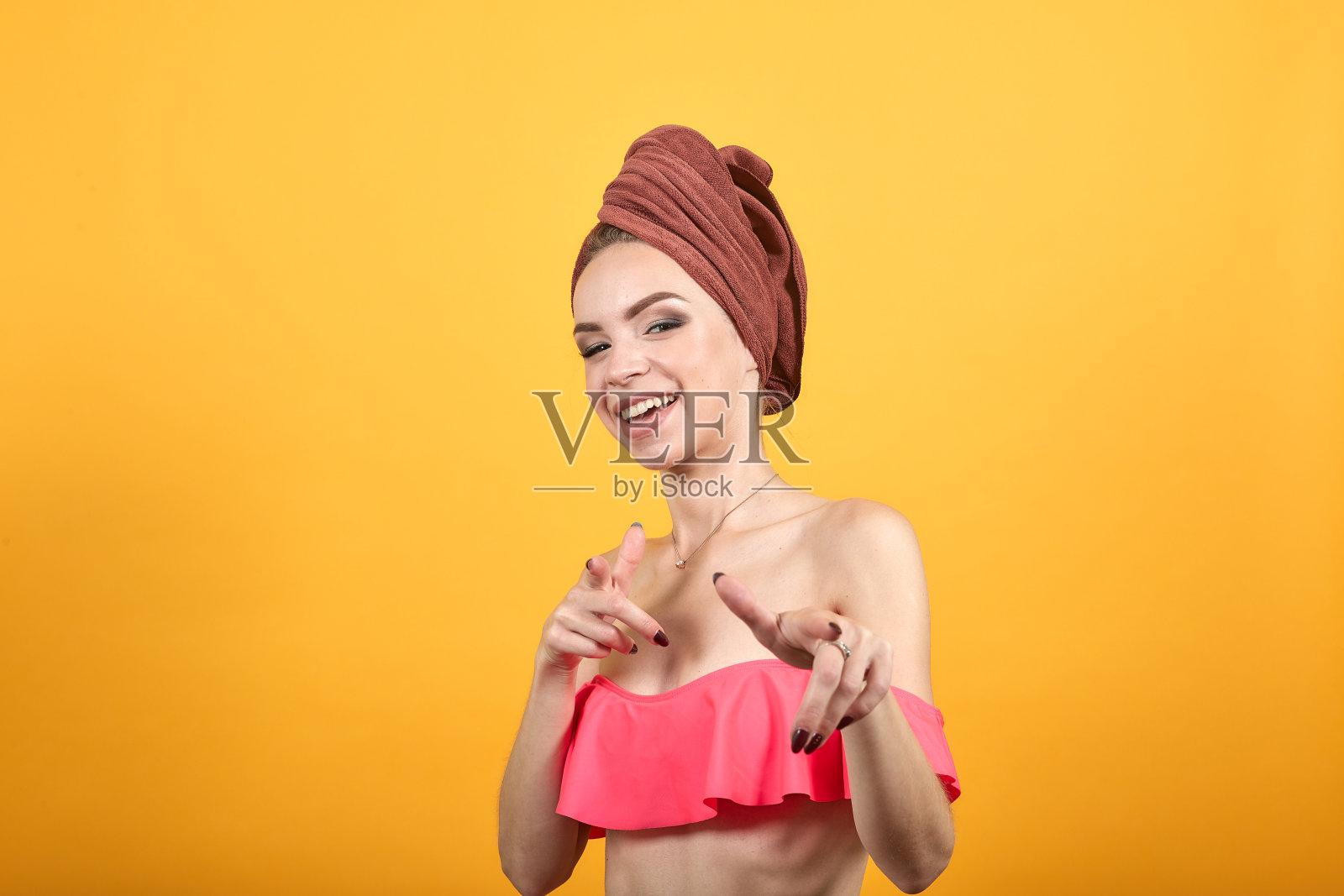 年轻的女孩与毛巾在她的头在孤立的橙色背景显示情绪照片摄影图片