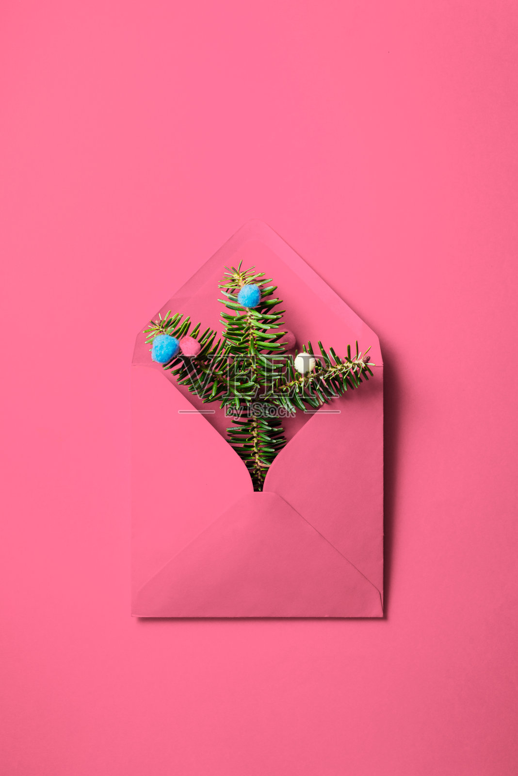 粉红色的信封，上面有冷杉树枝和粉红色背景上的装饰物。“圣诞nminimal组成。照片摄影图片