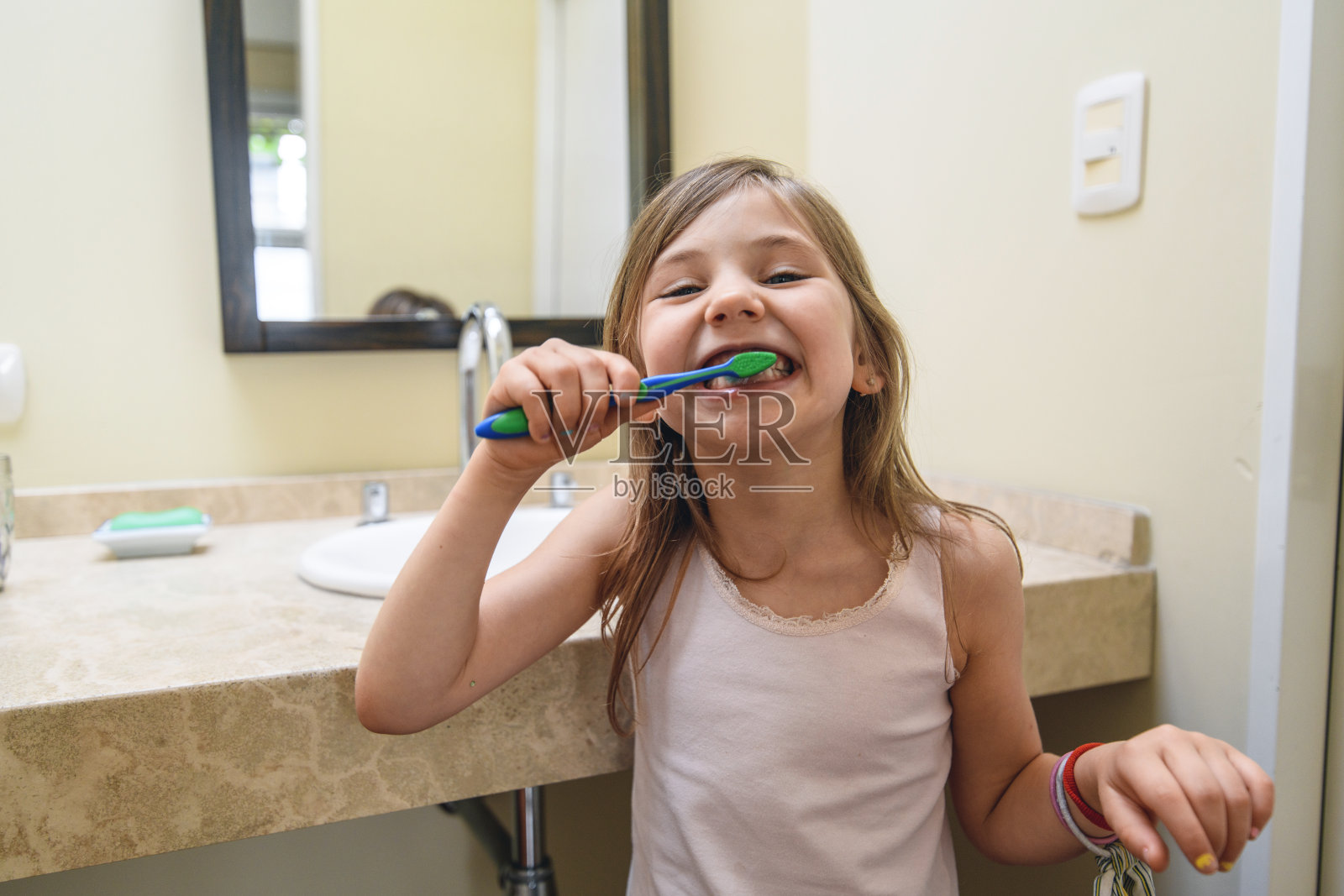 顽皮的小女孩在家里的浴室里刷牙照片摄影图片