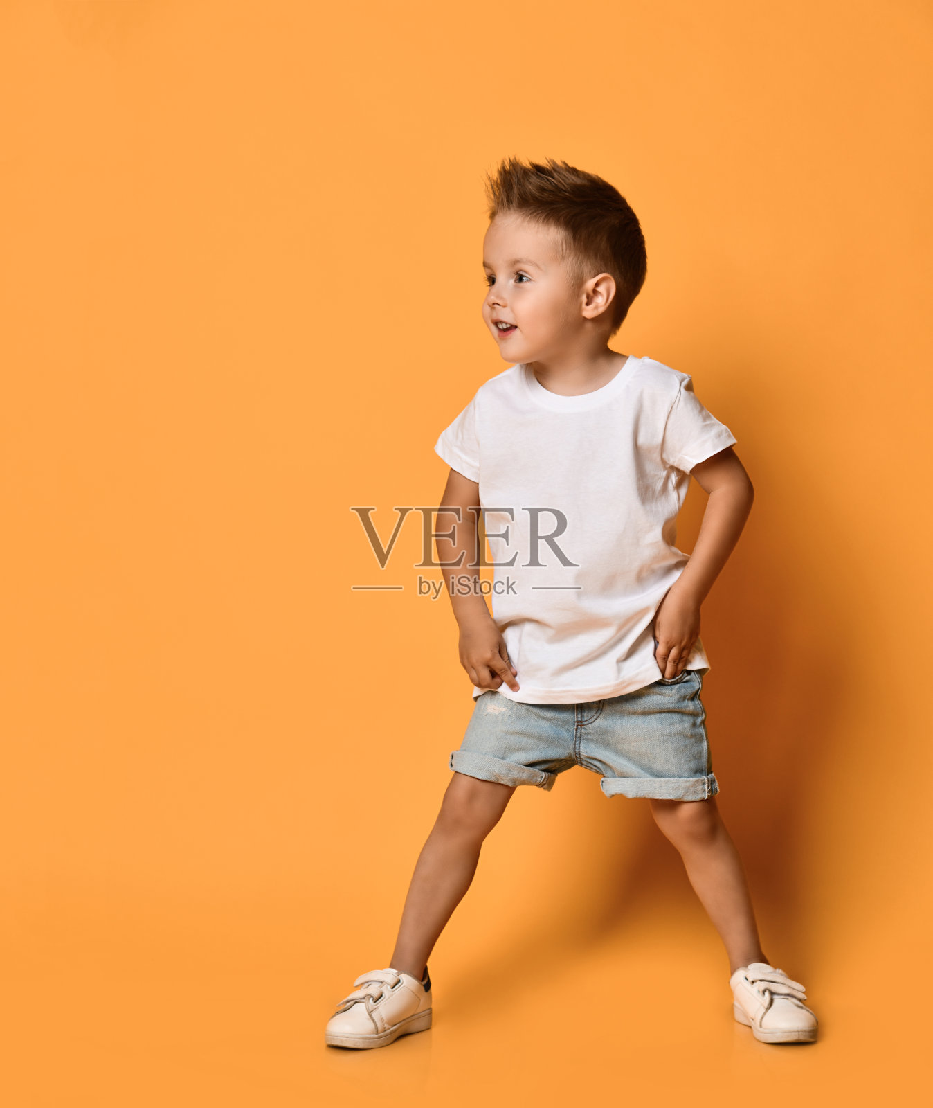 兴奋的孩子男孩在白色t恤和蓝色短裤正在看一些东西在黄色的免费拷贝空间准备运行照片摄影图片