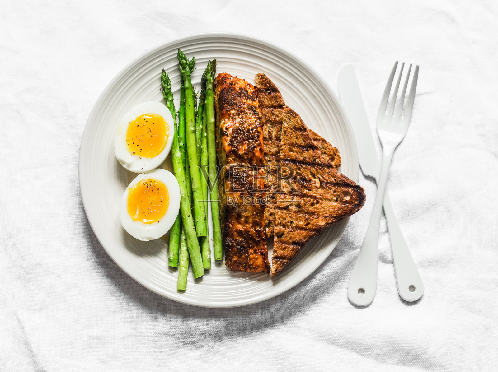 健康饮食午餐-烤鲑鱼，煮软蛋，芦笋和全麦面包在一个轻的背景，俯视图照片摄影图片