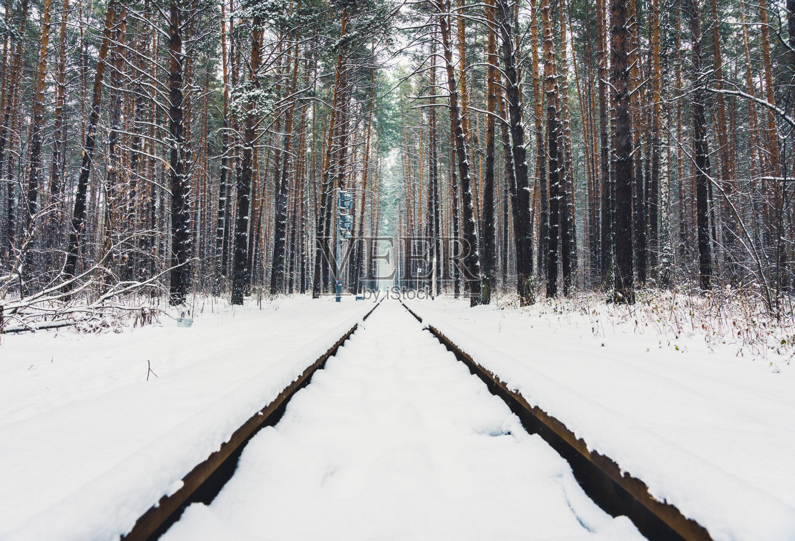 铁路穿过美丽的冬季森林。冬季景观与大雪。照片摄影图片