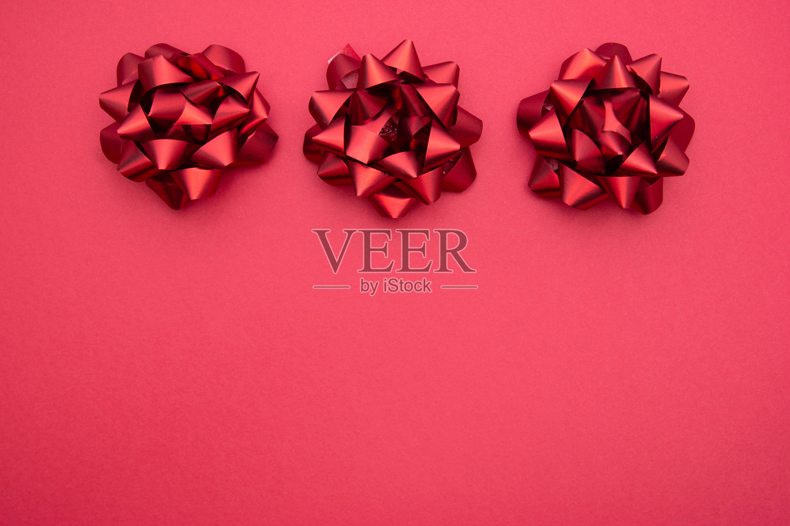 红丝带蝴蝶结在红色背景上，平躺着。派对，生日，圣诞节或情人节模式。平的。照片摄影图片