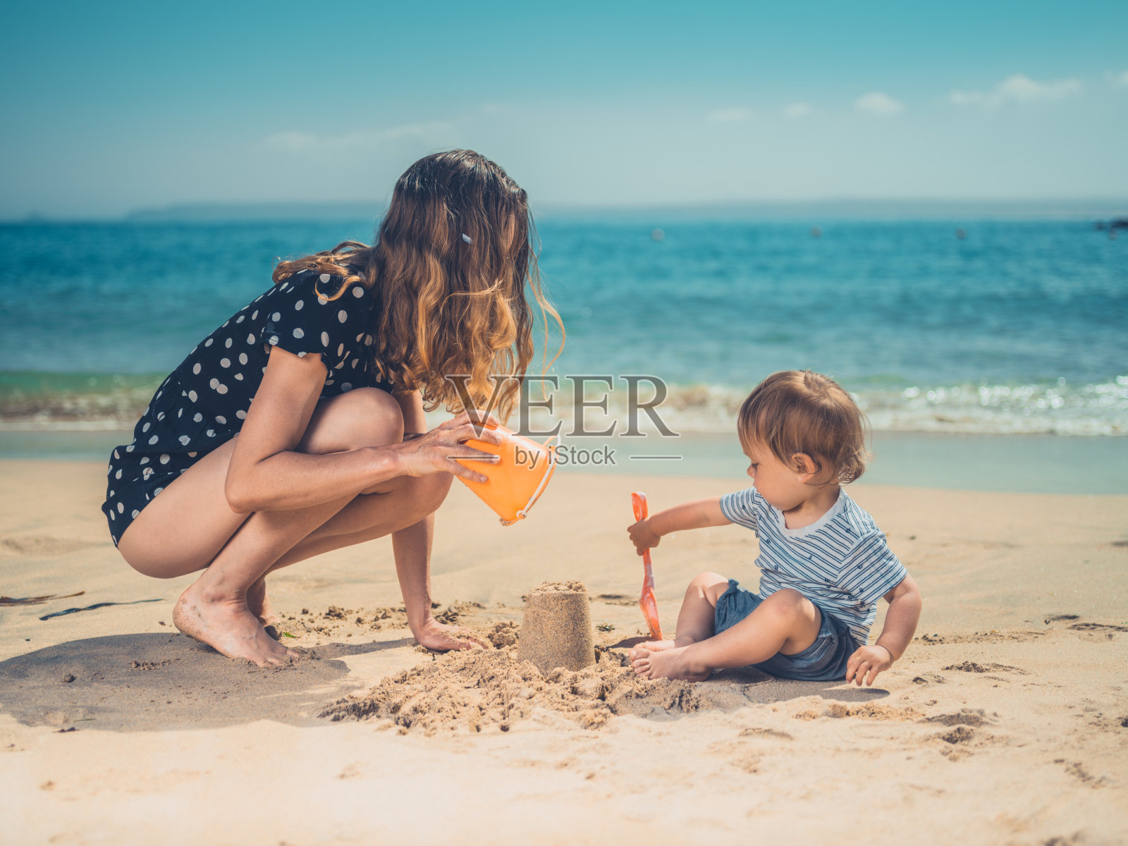 年轻的母亲和儿子在沙滩上玩耍照片摄影图片