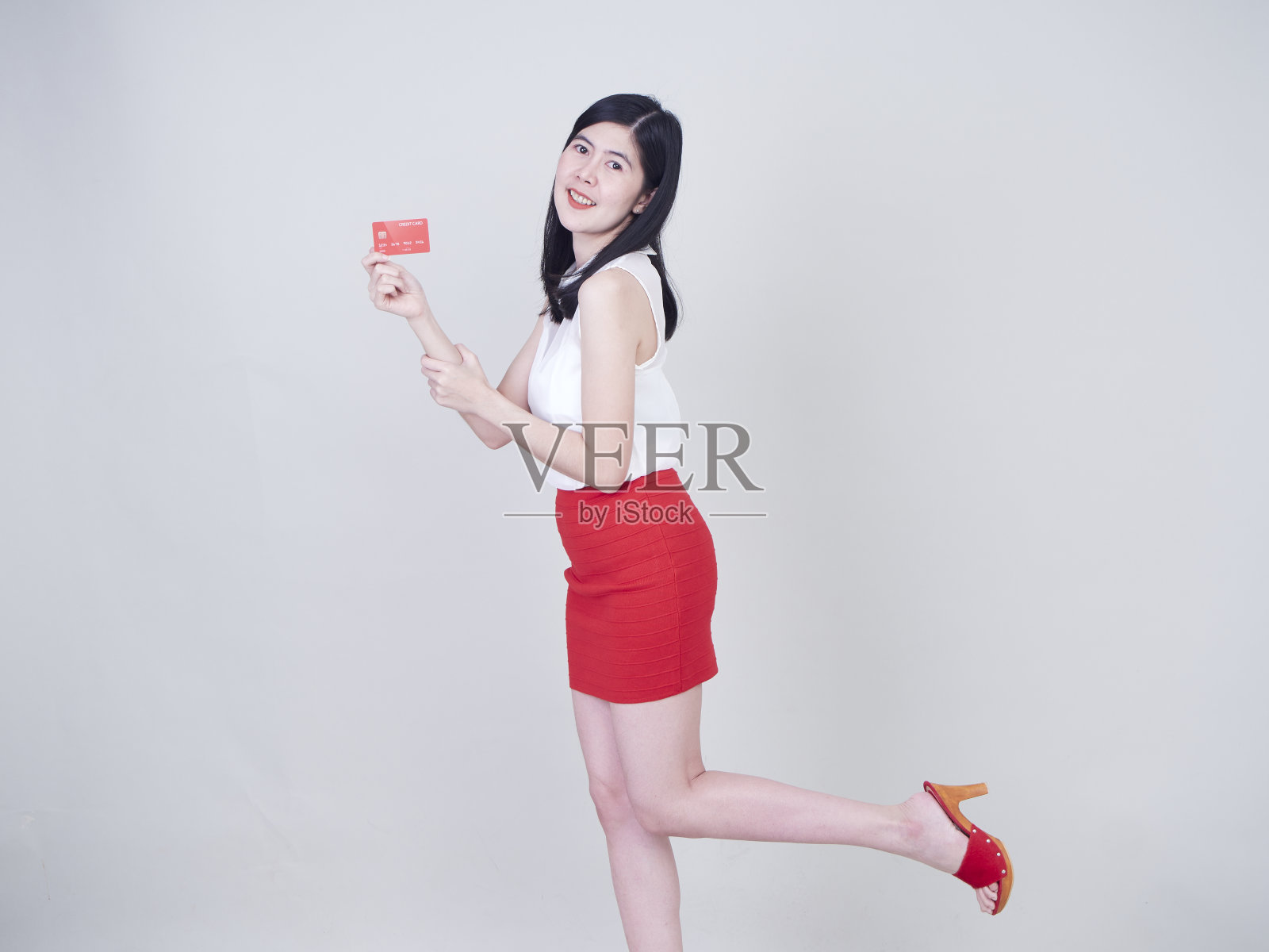 一个快乐微笑的女人，白色背景上的空白信用卡。消费者支出照片摄影图片