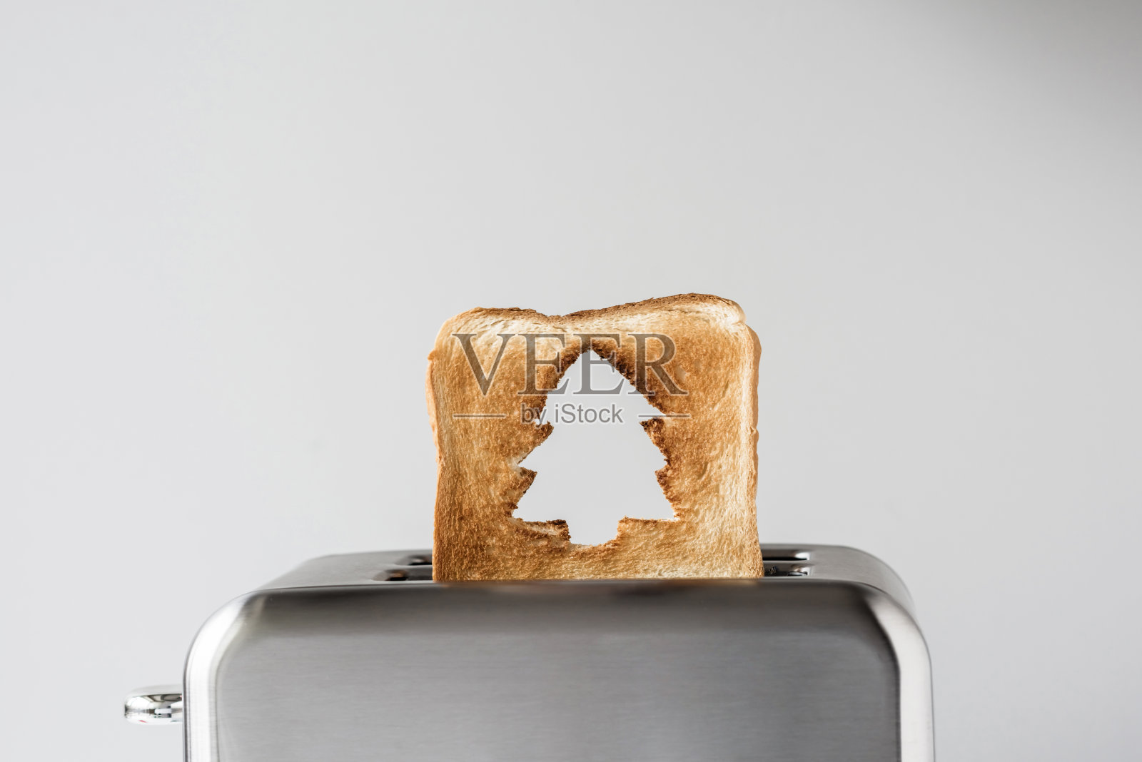 烤面包上的圣诞树洞，不锈钢复古烤面包机冒出来准备早餐。概念照片摄影图片