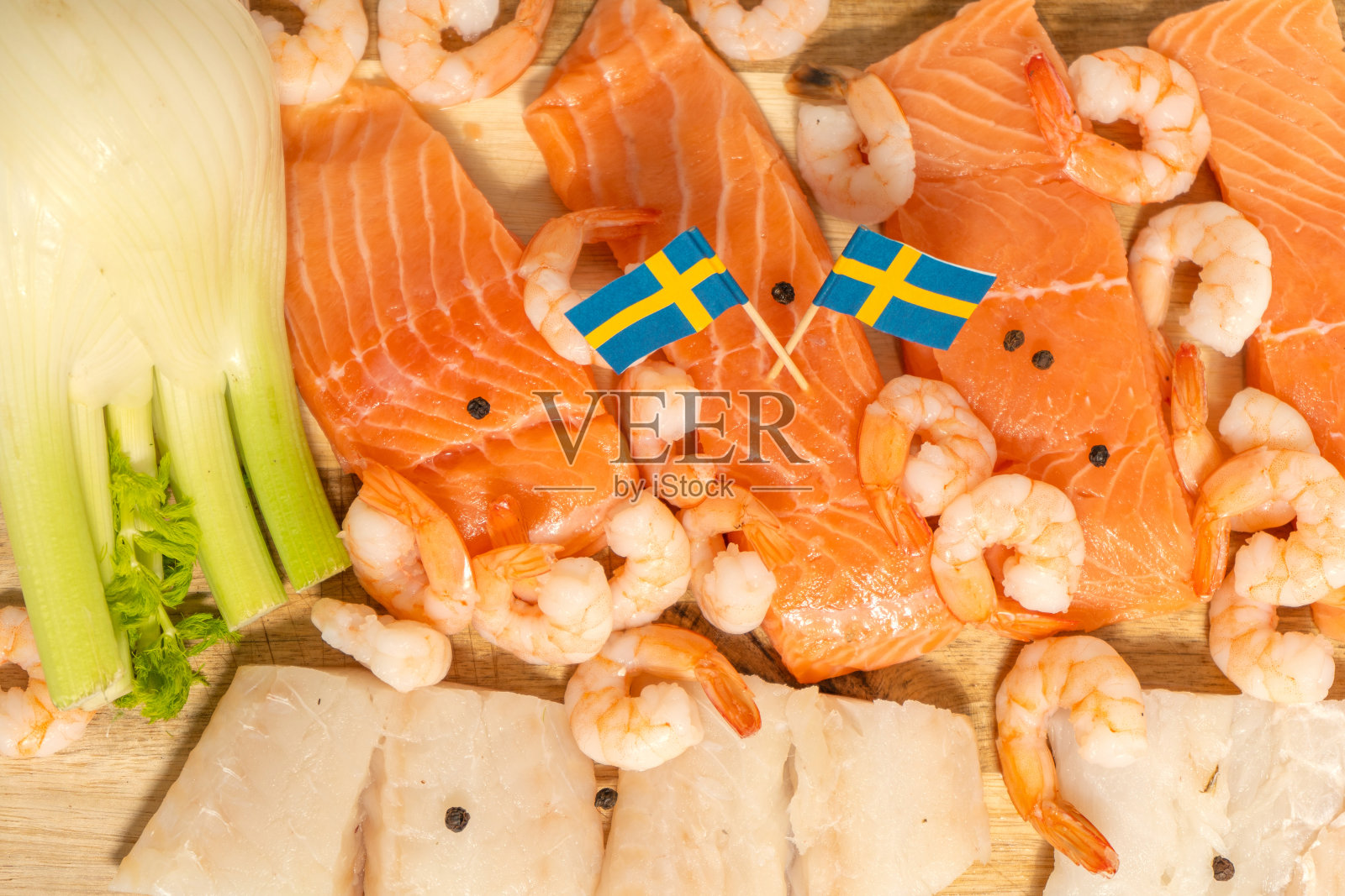 木板上放着鲑鱼、鳕鱼、虾和黑胡椒。瑞典的国旗。国家食品照片摄影图片