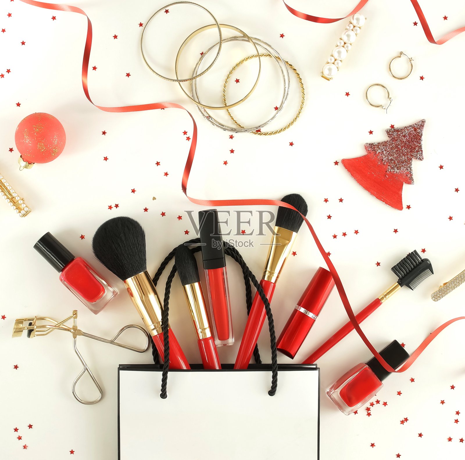 购物袋和配件的女性化妆在红色和圣诞装饰的白色背景俯视图，平躺，复制空间。黑色星期五，圣诞节促销概念。照片摄影图片