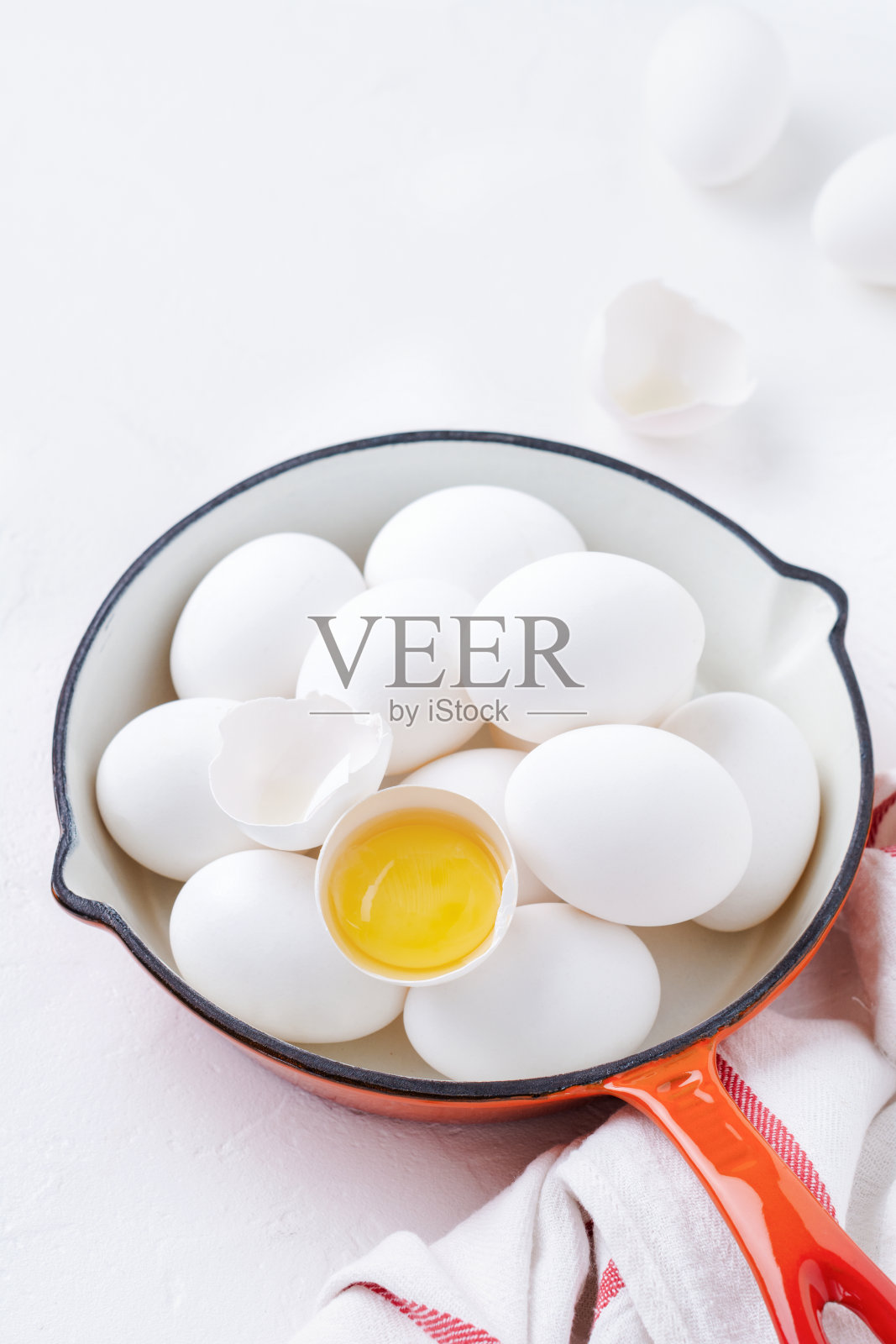 白色的生鸡蛋在红色的平底锅中，背景光线。前视图。照片摄影图片