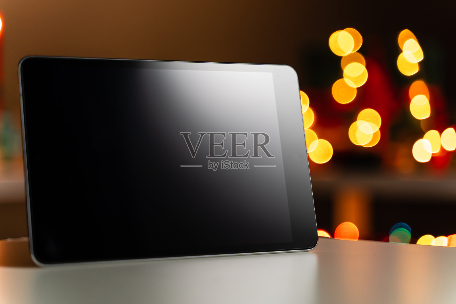 数码平板电脑前的散焦圣诞灯光背景，散焦照片摄影图片