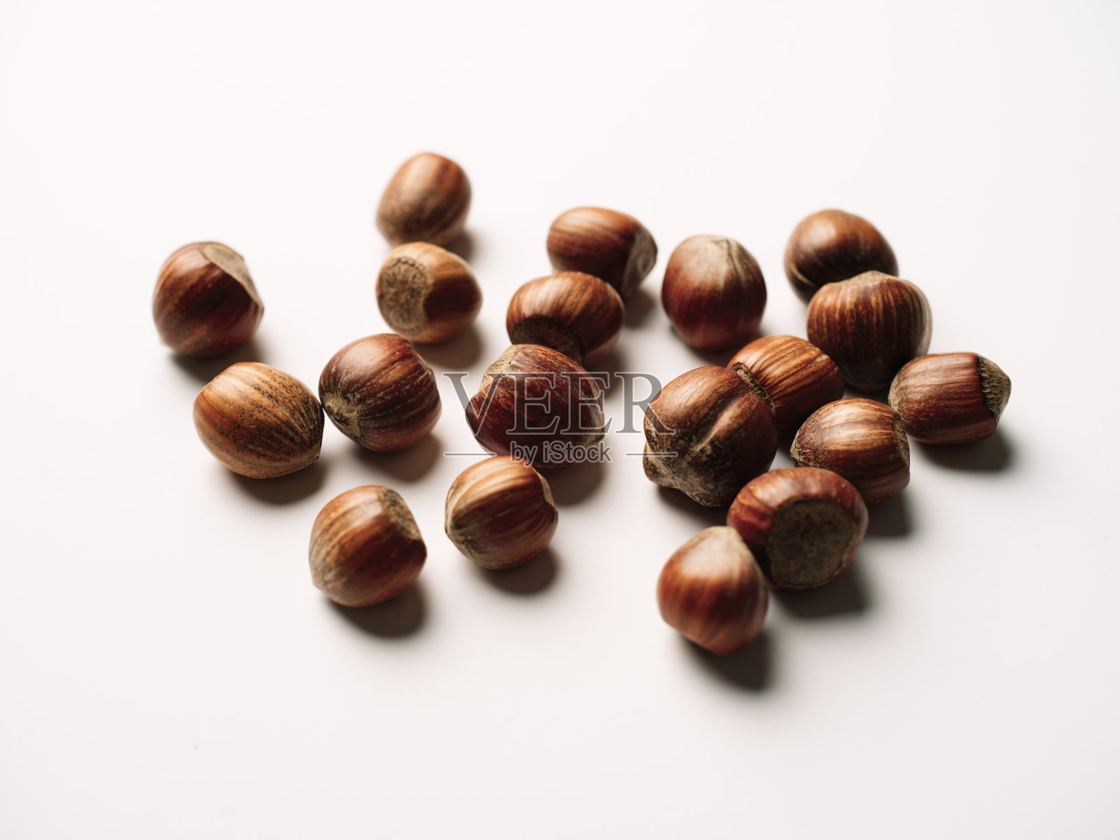 白色背景下散落的榛子。照片摄影图片