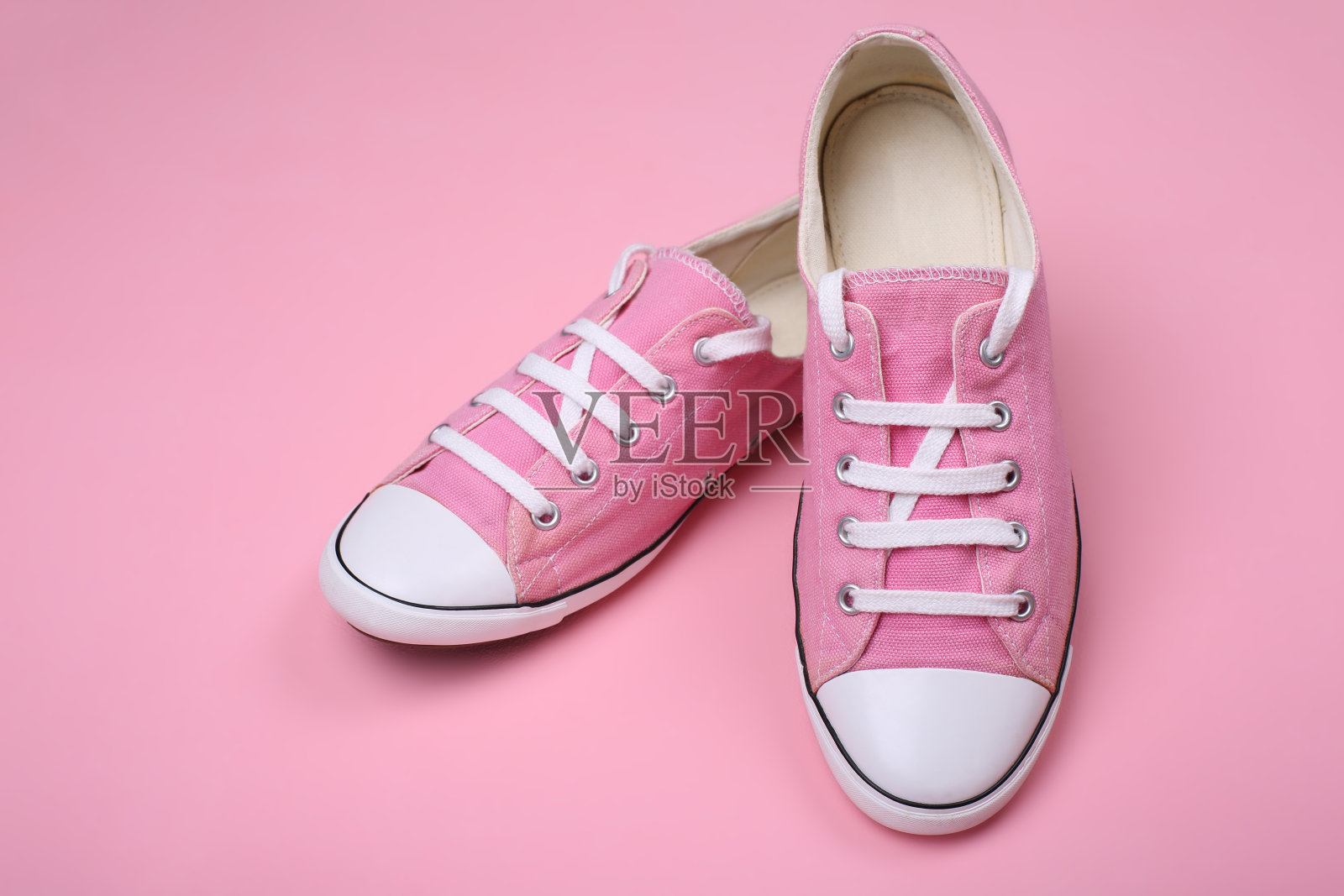 粉色背景上的粉色女运动鞋。特写镜头照片摄影图片