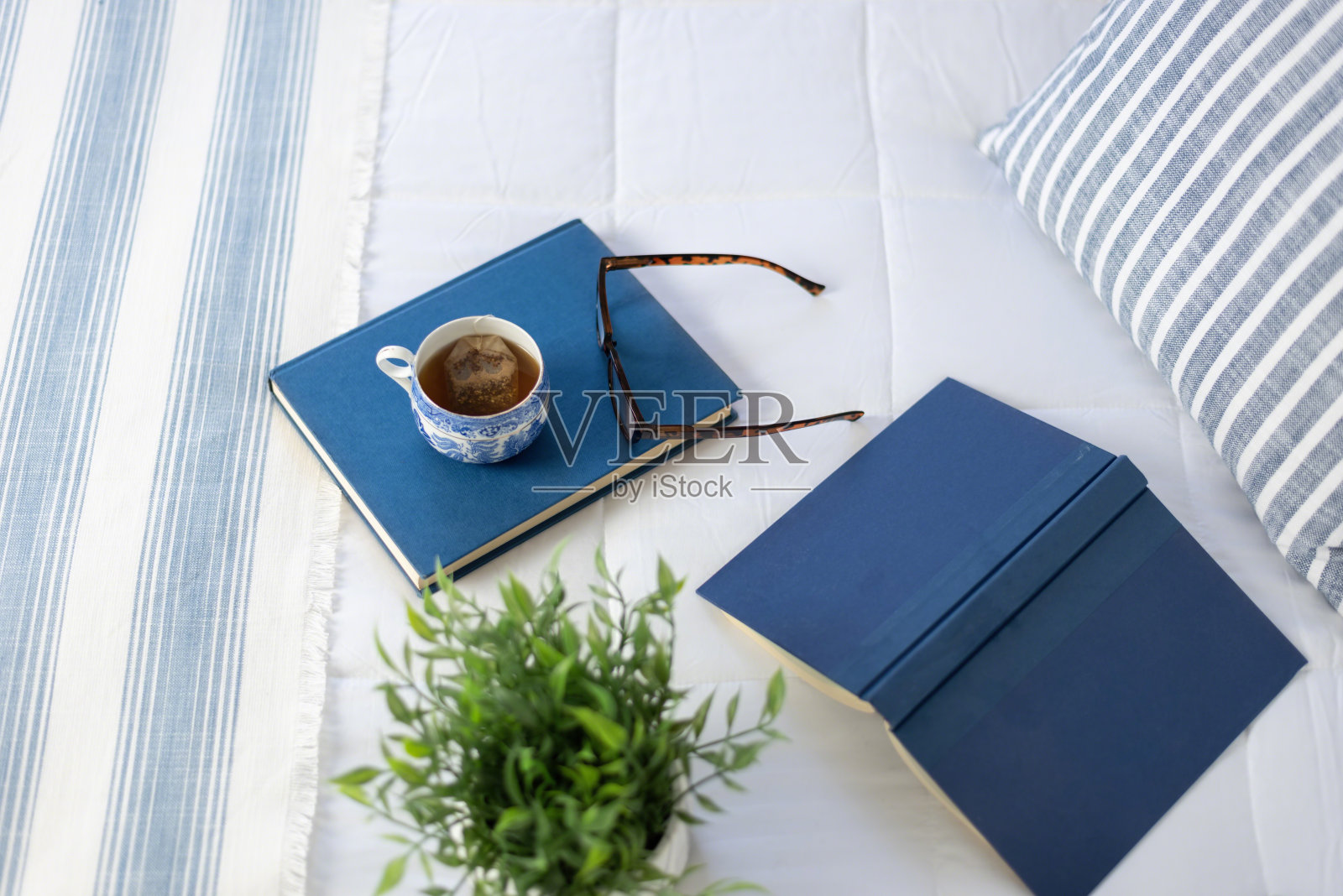 白色的床上放着蓝色的书，在家里放松照片摄影图片