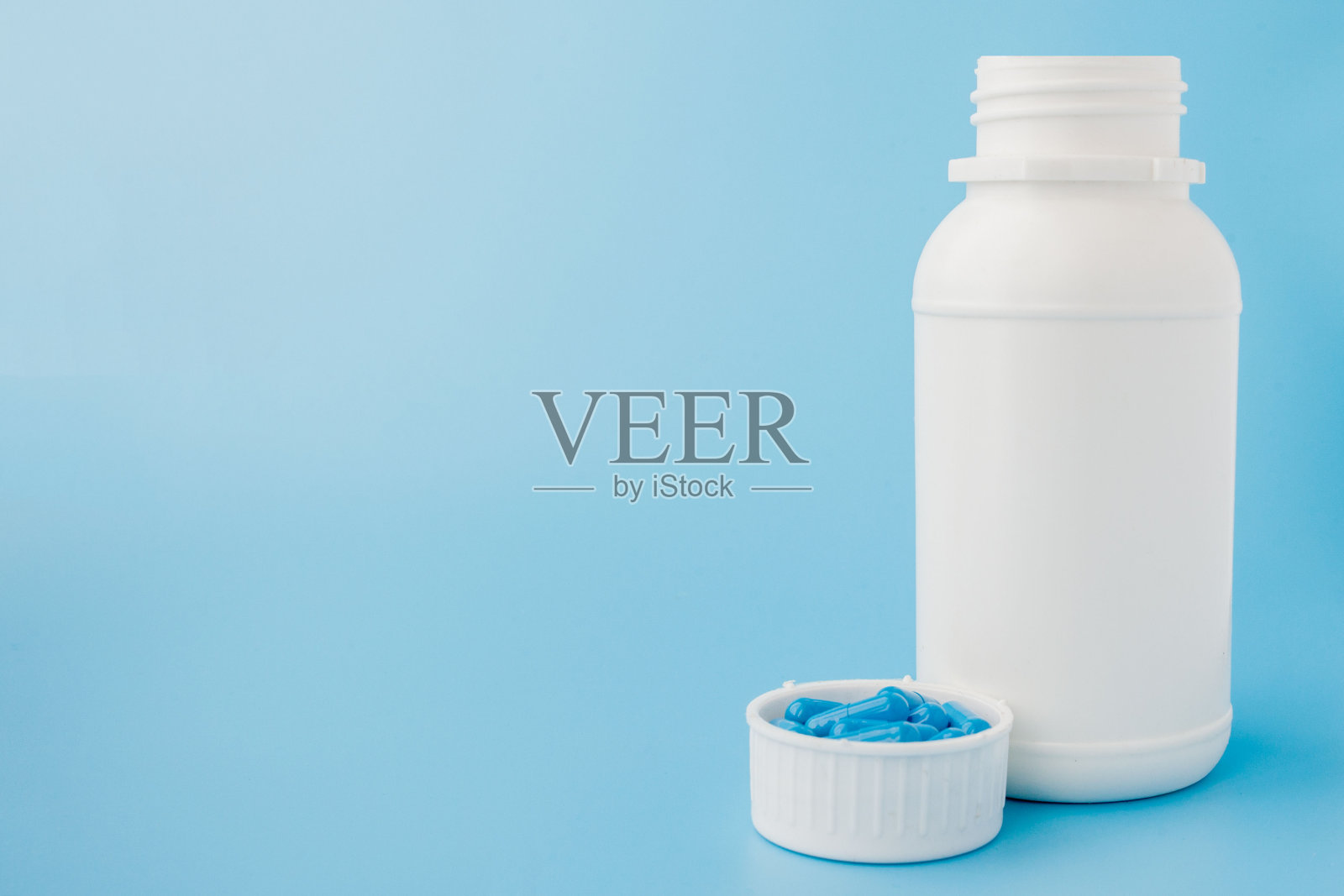 蓝色的胶囊，蓝色背景的药丸。白色罐子里的胶囊。维生素，妇女健康的营养补充照片摄影图片