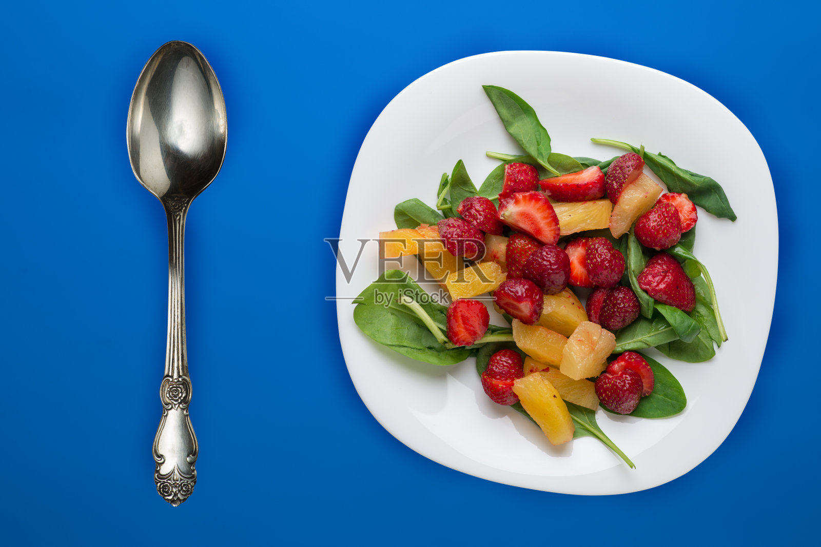 素食俯视图。菠菜沙拉，杏，草莓在一个白色的盘子在背景。照片摄影图片