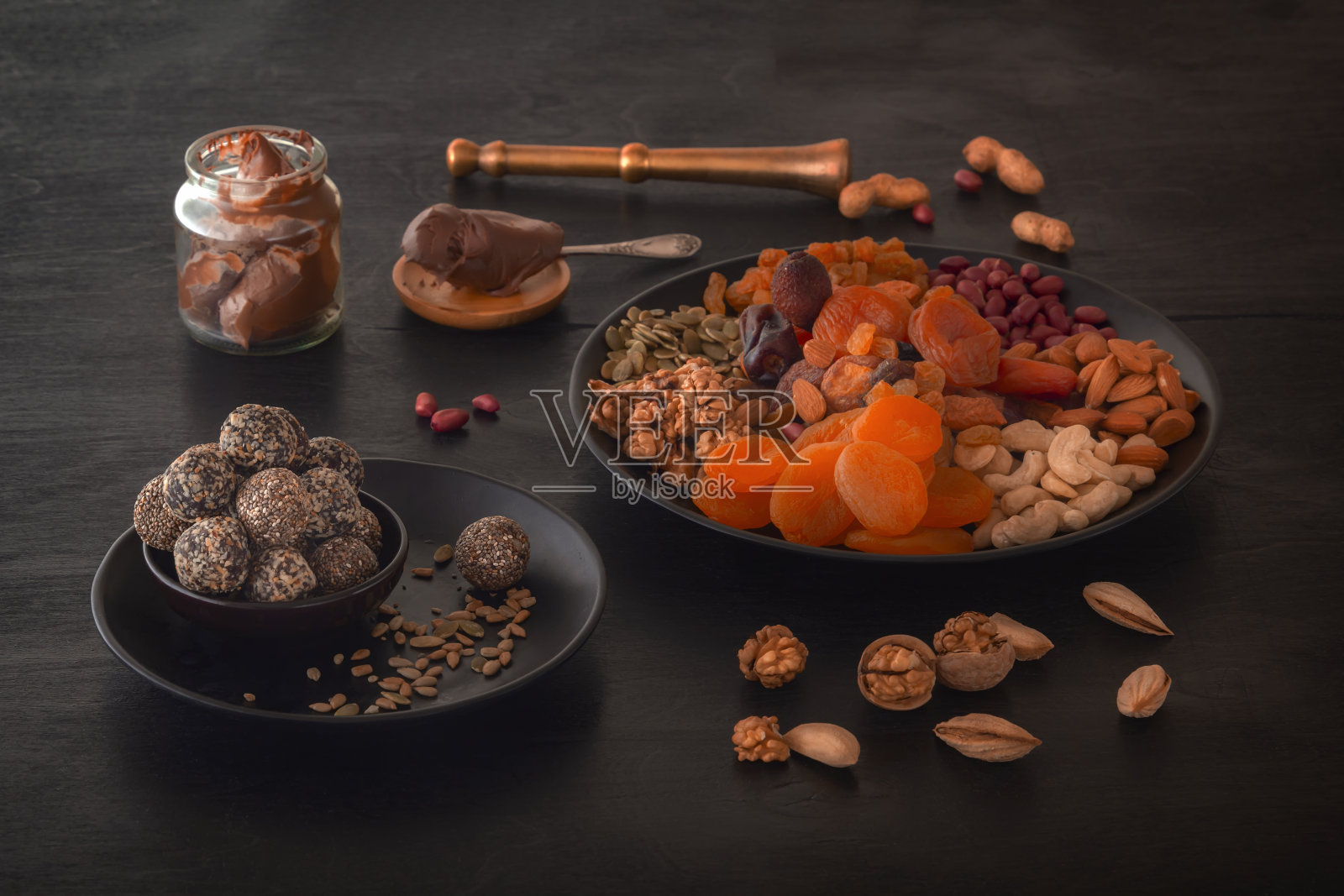 黑色的桌子上放着天然健康的能量食物、巧克力酱和干果。照片摄影图片