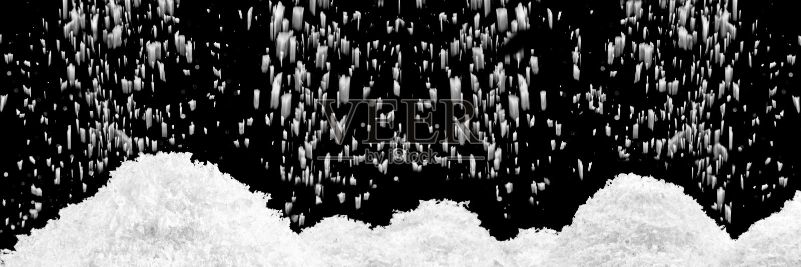 黑色背景上的雪堆和飘落的雪。雪山。照片摄影图片