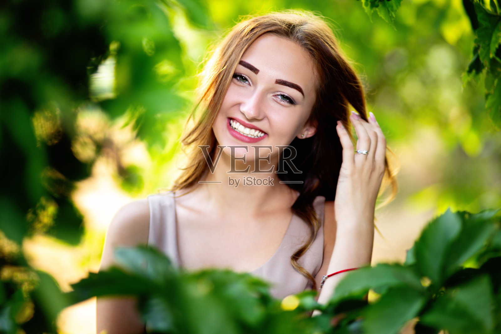 一个美丽的女孩在一个夏天的花园，年轻的女人在绿色的树叶照片摄影图片