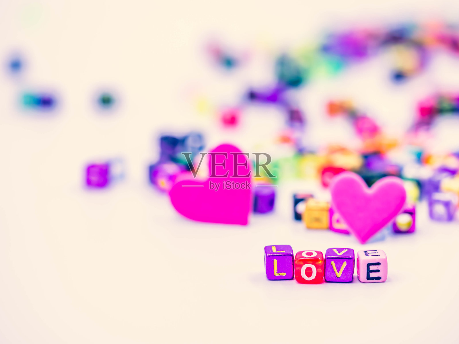 交叉处理的色调，特写，微距摄影彩色的小塑料字母骰子的爱字与模糊生动的白色背景，充满活力的粉色心形爱，浪漫，情人节的想法。照片摄影图片