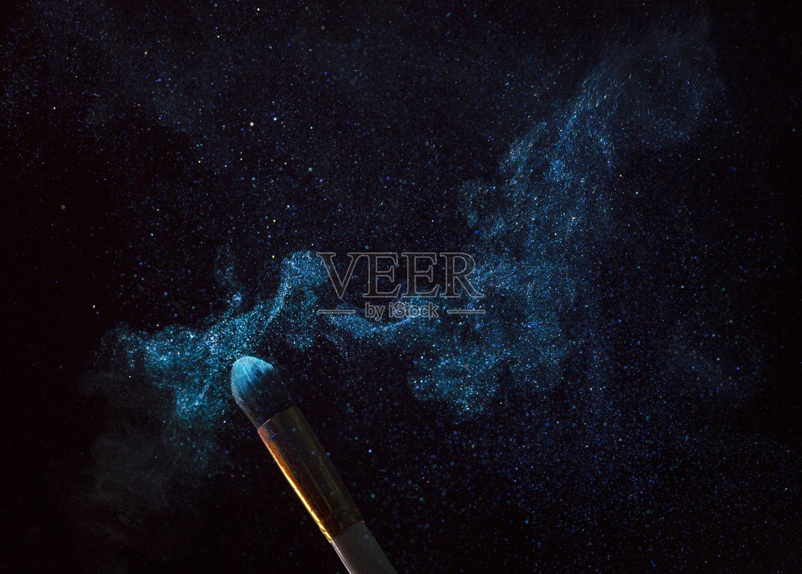 化妆刷与蓝色粉末爆炸隔离在黑色背景照片摄影图片