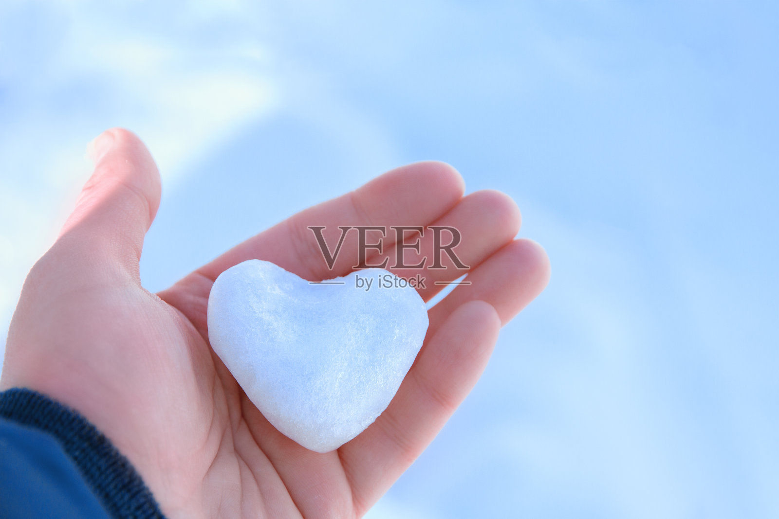 冰小雪心在摊开孩子们的手掌上，浅蓝色的背景copyspace照片摄影图片