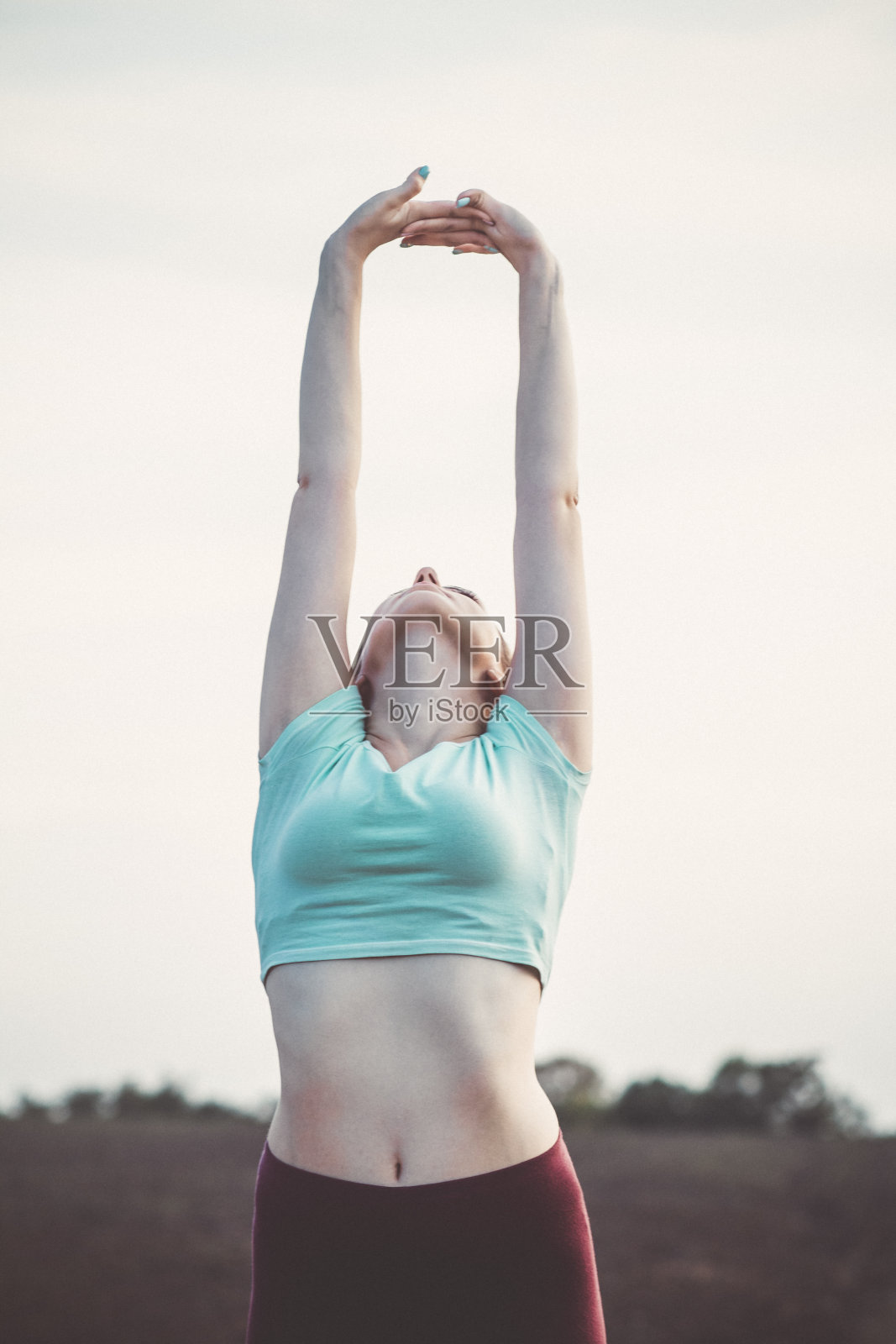 苗条的年轻女子穿着运动服在田野里锻炼和伸展双手，女孩从事户外运动，概念健康的生活方式和女性美照片摄影图片