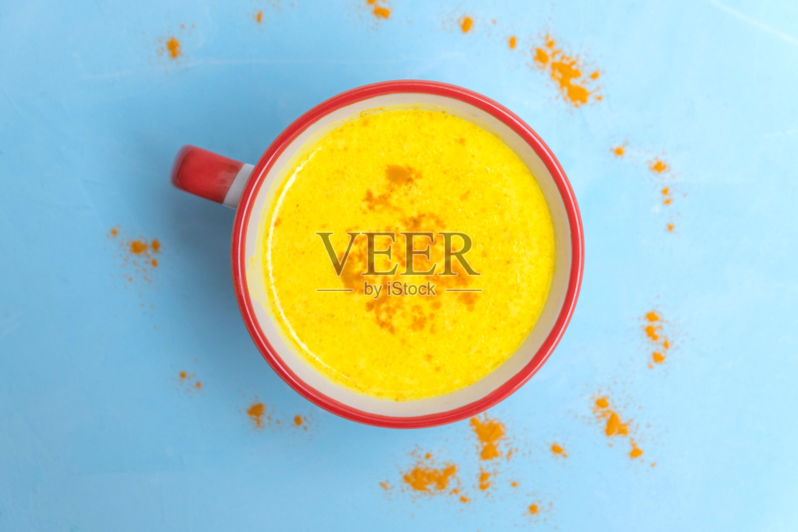 温暖健康的阿育吠陀饮姜黄金色牛奶与姜黄粉在浅蓝色的桌子上的特写图像。带有拷贝空间的图像，俯视图照片摄影图片