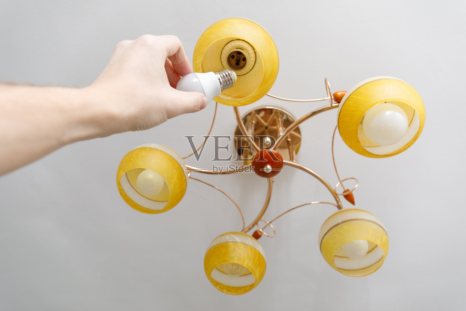 用手把新灯泡拧到顶灯上照片摄影图片