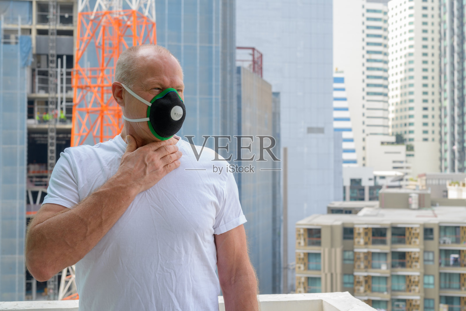 在城市里，老人戴着面罩以保护自己免受污染和烟雾的影响照片摄影图片