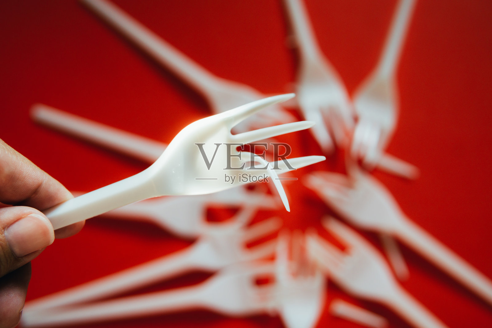 红色背景上有很多塑料叉子。照片摄影图片