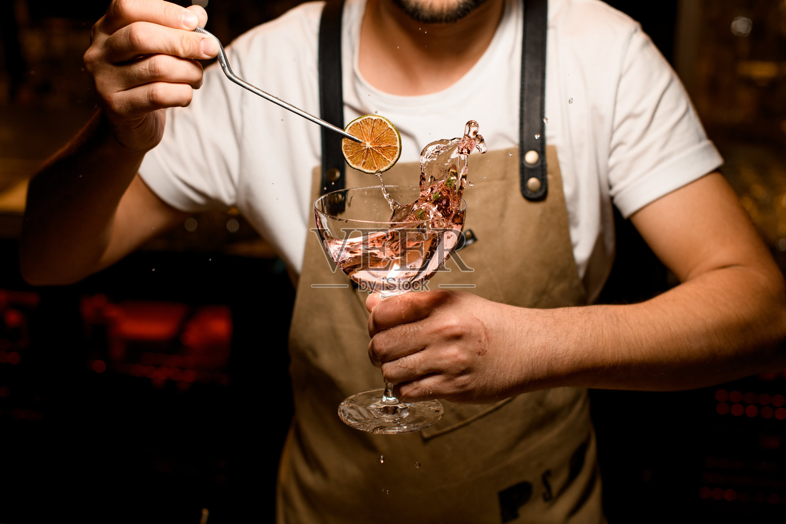 特写的调酒师装饰溅起的鸡尾酒与橙色照片摄影图片