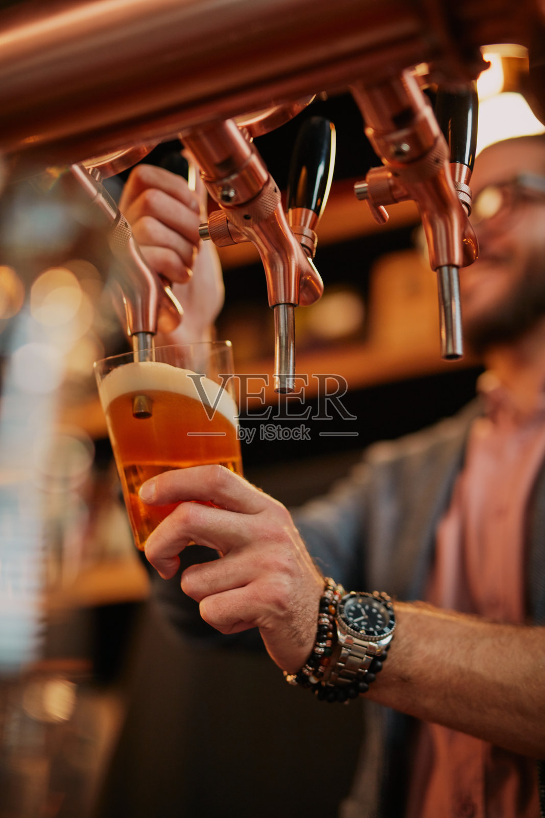 酒吧间招待员倒啤酒。照片摄影图片