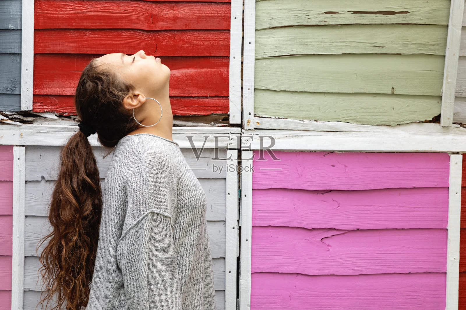 后面有彩色栅栏的女孩的侧面肖像照片摄影图片