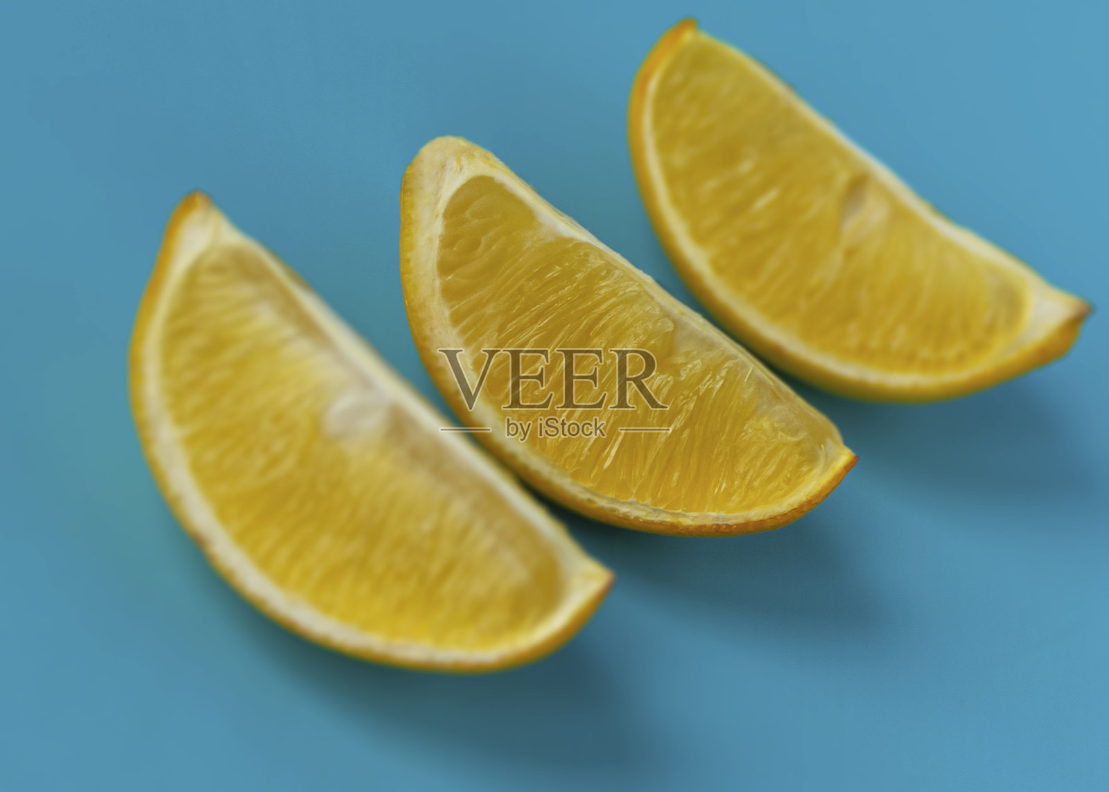 蓝色背景下鲜亮多汁的柠檬片。黄色的柠檬。柑橘类。照片摄影图片