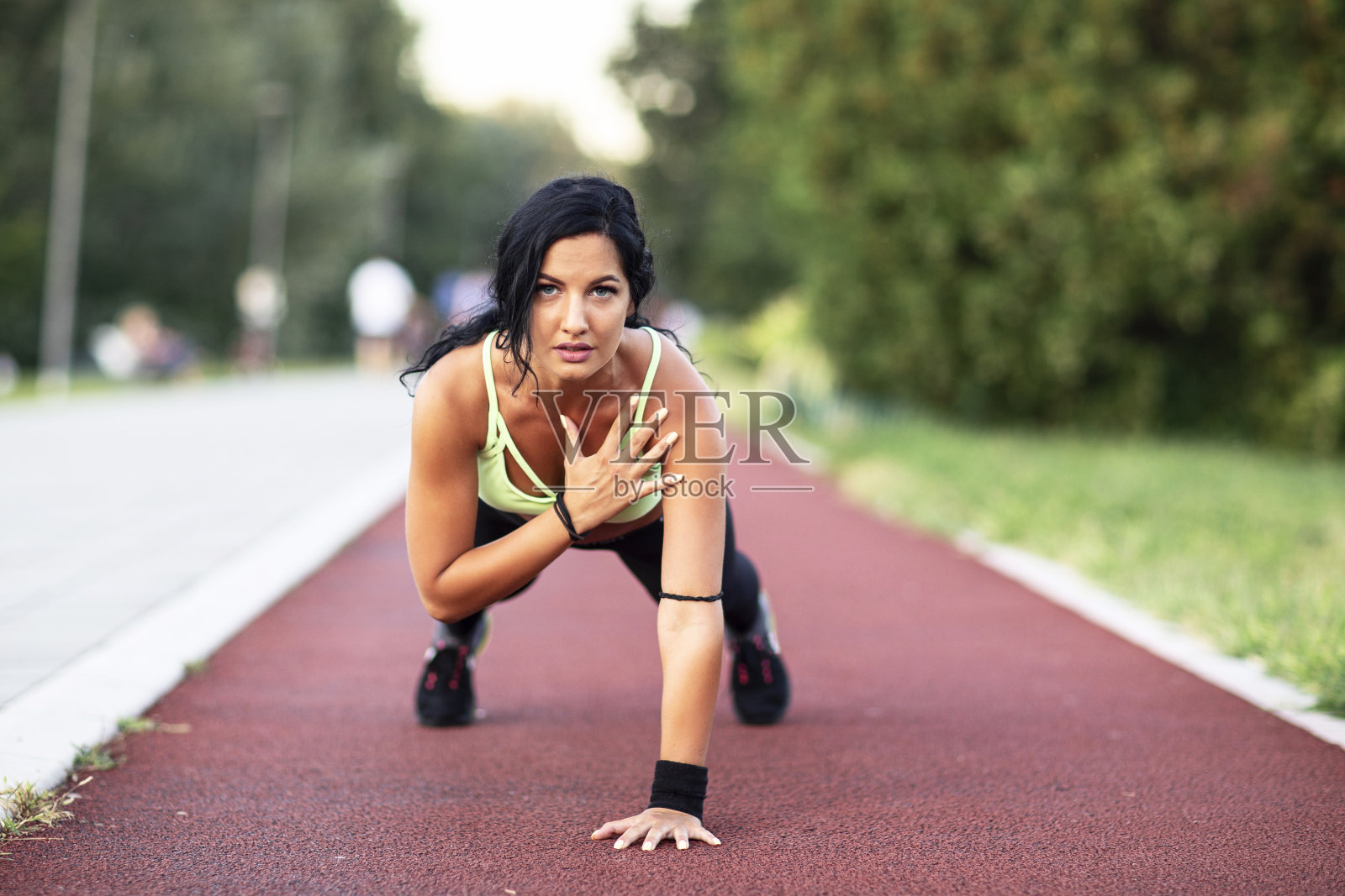长黑发的女人在公园的格子跑道上锻炼照片摄影图片