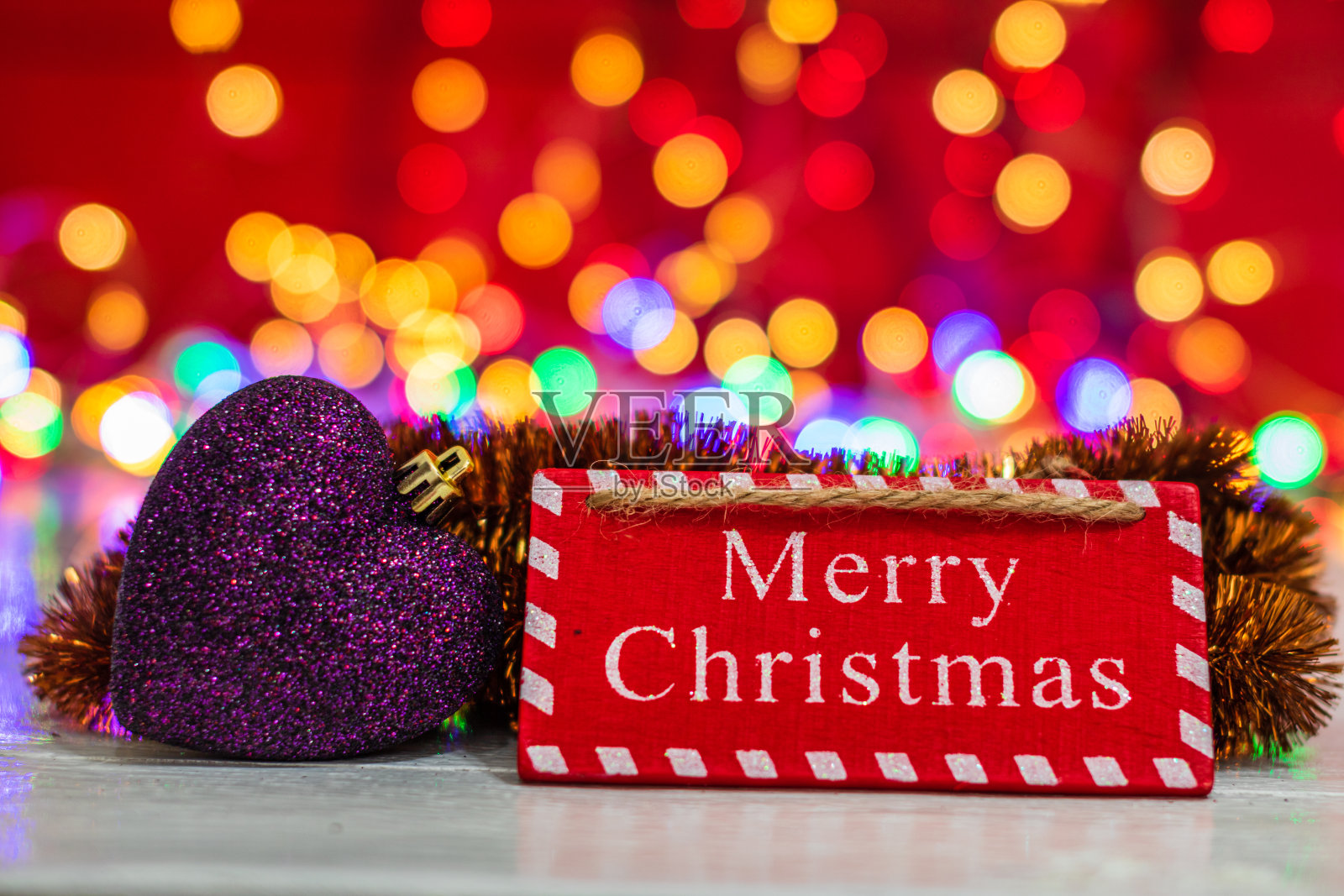 圣诞快乐木制标志和五颜六色的心形装饰品。圣诞合成上模糊的灯光背景。照片摄影图片