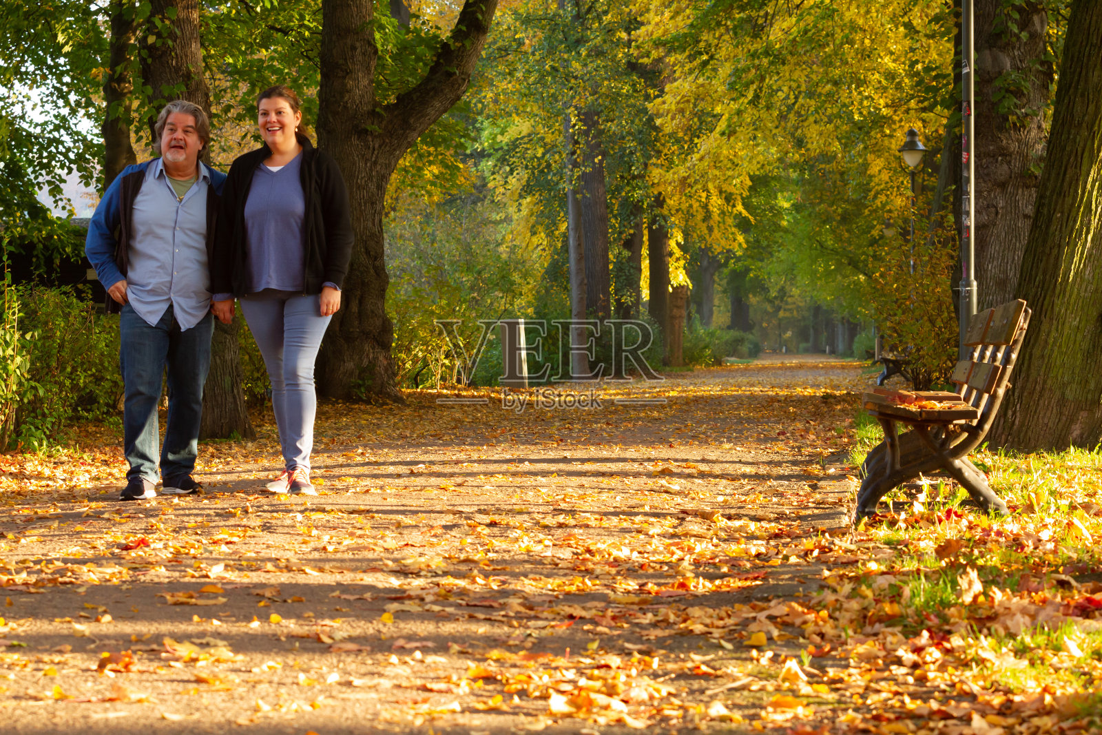 一对情侣秋天在公园散步照片摄影图片