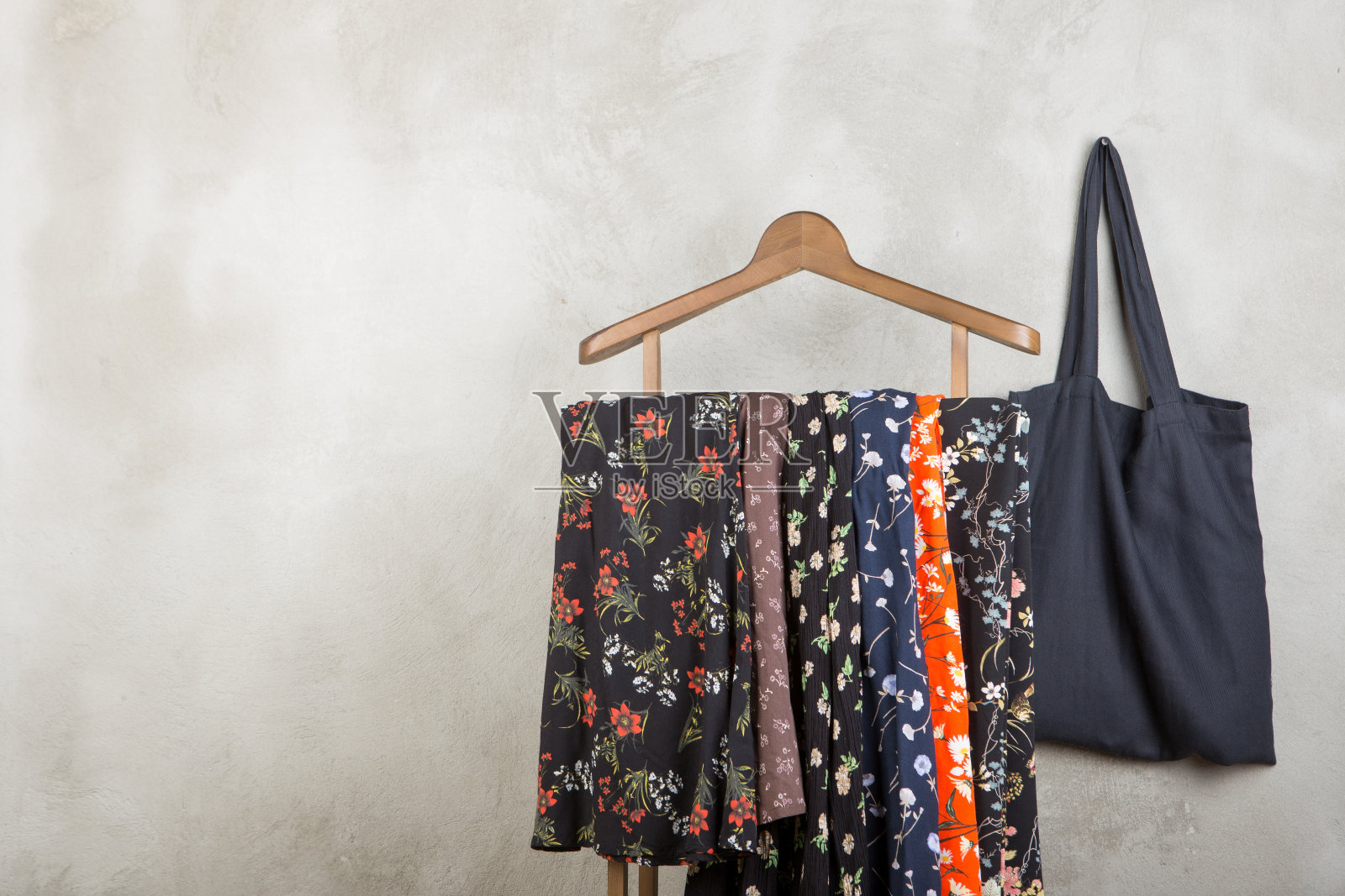 购物和风格概念-衣架时髦的裙子在印花和黑色环保手提袋在灰色混凝土背景照片摄影图片