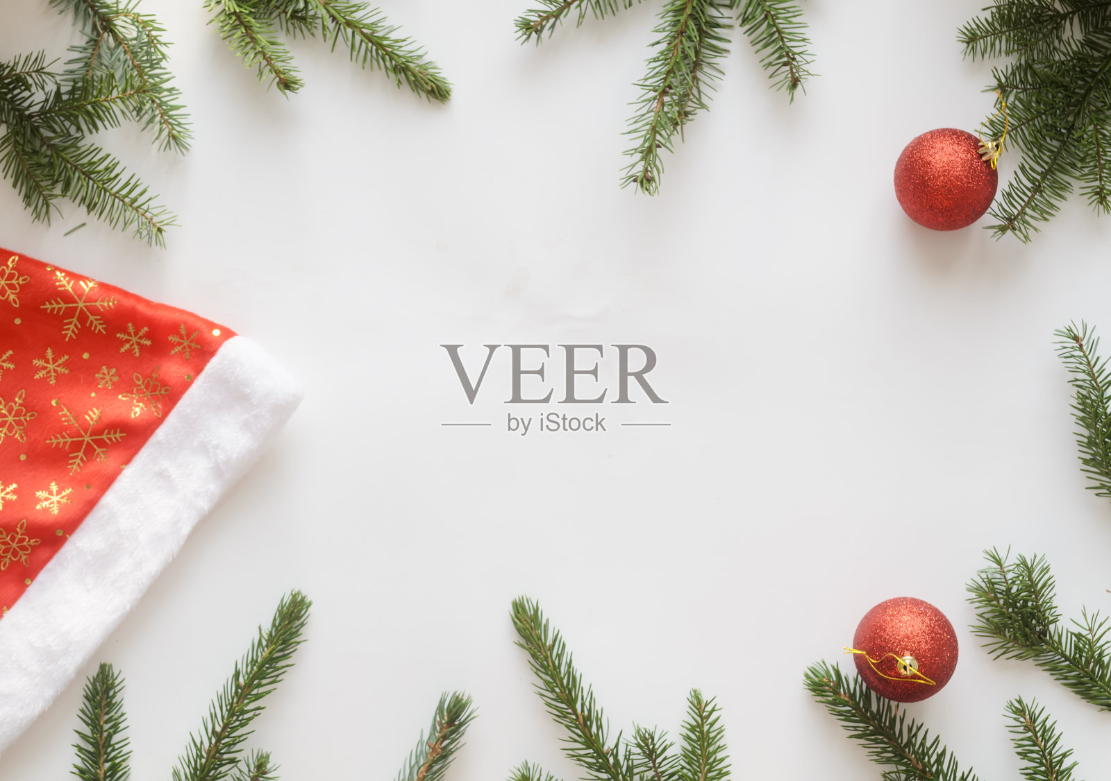 圣诞和新年作文。俯视图，圣诞帽，两个红色的球和圣诞树的树枝在白色的背景，copyspace在中心。照片摄影图片