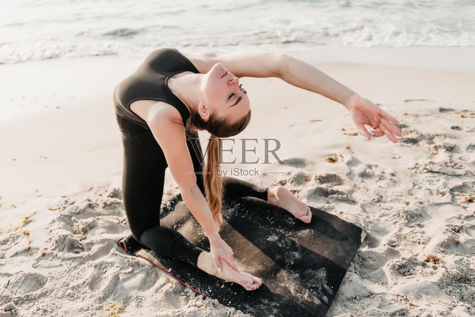 年轻的运动健康的女人在海边做瑜伽照片摄影图片