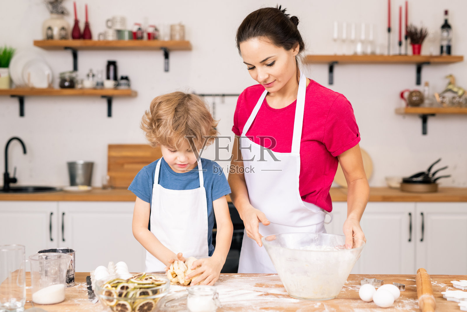 可爱的小男孩一边帮妈妈揉面团做饼干照片摄影图片