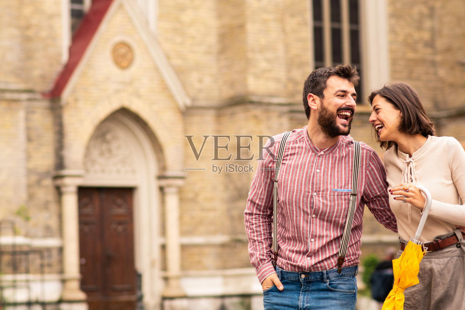 一对情侣在街上走着，笑着拥抱着。照片摄影图片