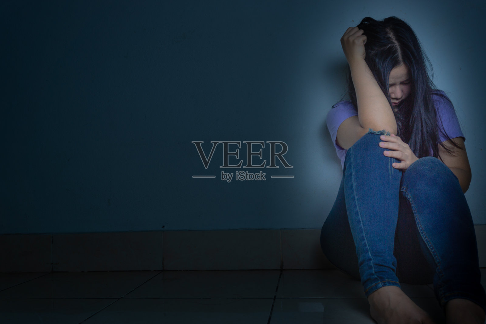 悲伤的女人抱着膝盖独自坐在黑暗的房间里哭泣。抑郁，不快乐，紧张和焦虑障碍的概念照片摄影图片