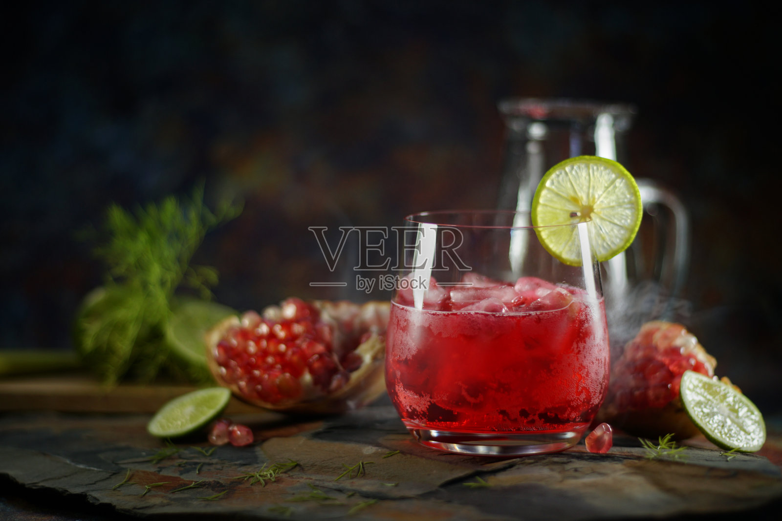 石榴汁柠檬苏打水与石榴籽在桌子上的静物摄影。在摄影棚拍摄，低调的画面。照片摄影图片